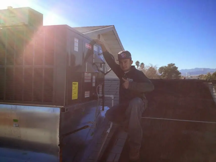 HVAC technician performing AC Tune-Up on a rooftop unit in Clifton Heights